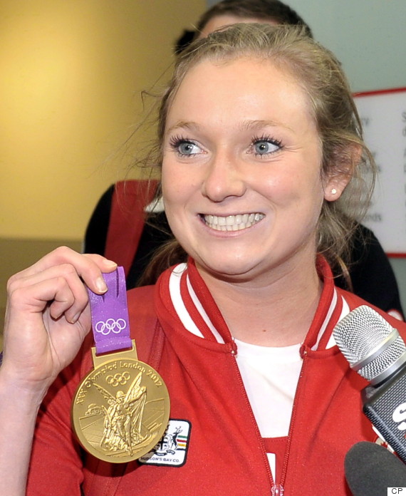 Canadian Olympic gold medalist Rosie MacLennan holds up her medal as she at Pearson airport in Toronto, August 13, 2012. Life is pretty much back to normal for Canada's lone gold medallist from the London Olympics. THE CANADIAN PRESS/J.P. Moczulski